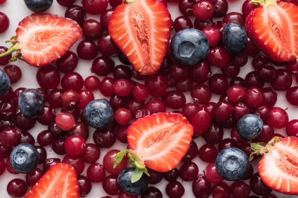 Vue de dessus des canneberges rouges, fraîches et mûres, des fraises coupées et des bleuets entiers — Photo de stock