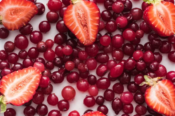 Draufsicht auf rote, frische und reife Preiselbeeren, geschnittene Erdbeeren — Stockfoto