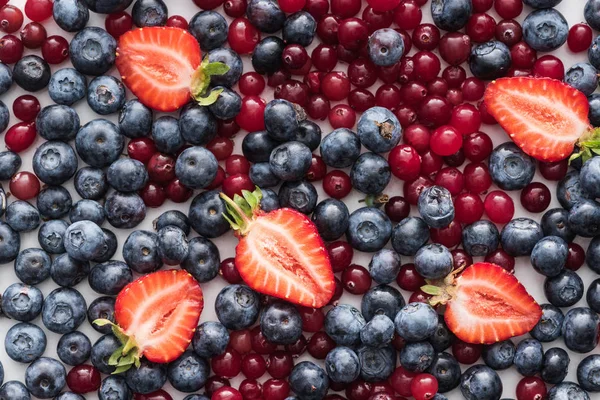 Draufsicht auf rote, frische und reife Preiselbeeren, geschnittene Erdbeeren, Blaubeeren — Stockfoto