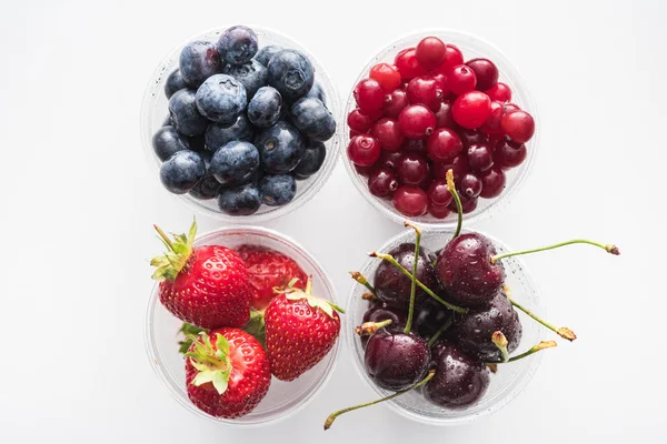 Top view of cranberries, strawberries, blueberries and cherries in plastic cups — Stock Photo