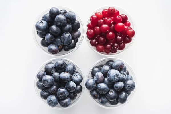 Top view of whole cranberries and sweet blueberries in plastic cups — Stock Photo