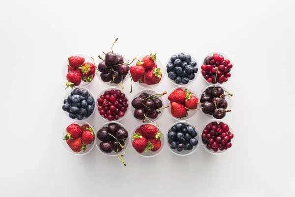 Top view of whole cranberries, sweet strawberries, blueberries and cherries in plastic cups — Stock Photo