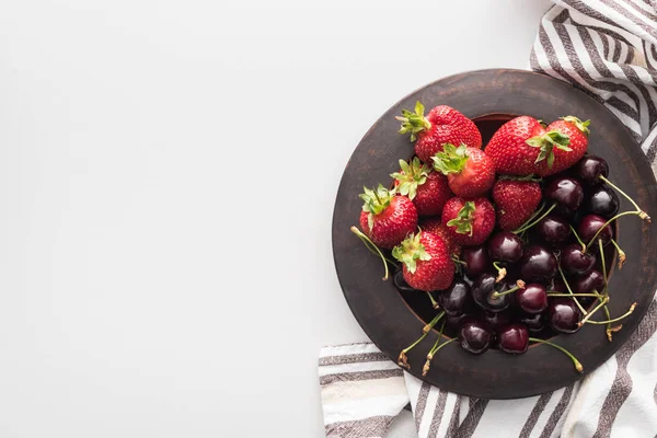 Vista superior de fresas enteras y cerezas dulces en el plato - foto de stock