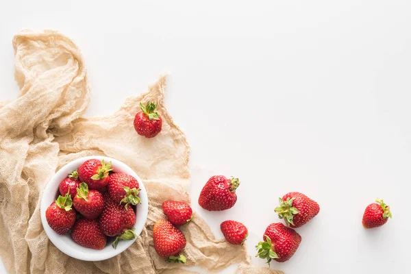 Top view of whole and red strawberries on bowl and beige cloth — Stock Photo