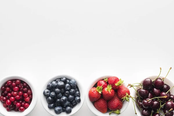 Top view of sweet cranberries and blueberries, strawberries and cherries on bowls — Stock Photo