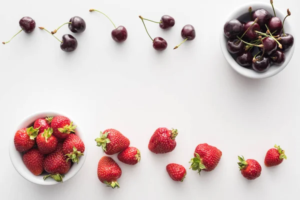Вид зверху на солодку полуницю і цілі вишні на мисках — стокове фото