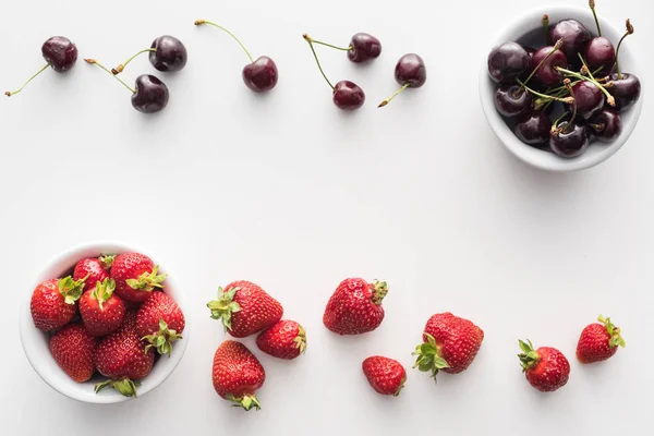 Top view of sweet strawberries and whole cherries on bowls — Stock Photo