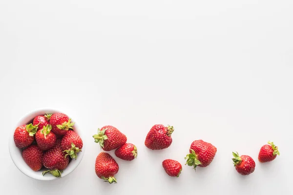 Ansicht von süßen und ganzen Erdbeeren auf Schüssel auf weißem Hintergrund — Stockfoto