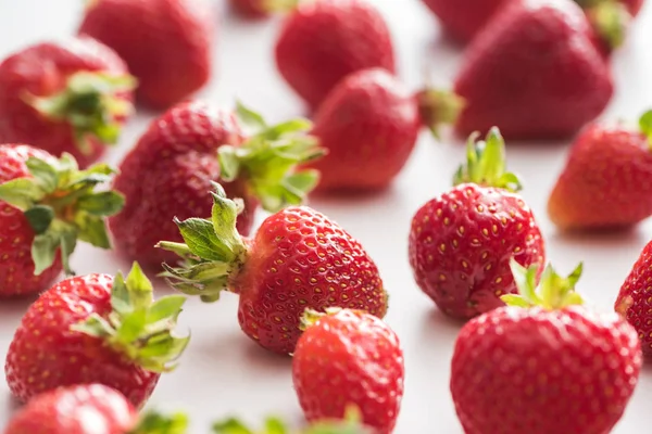 Selektiver Fokus von ganzen und roten Erdbeeren auf weißem Hintergrund — Stockfoto