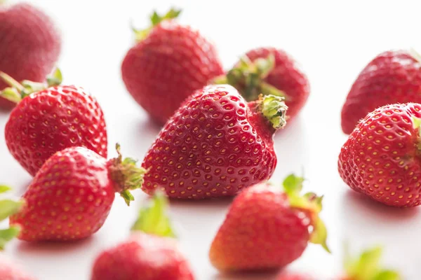 Selektiver Fokus von ganzen und roten Erdbeeren auf weißem Hintergrund — Stockfoto