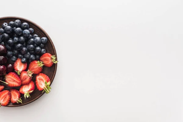 Vista superior de arándanos dulces, cerezas y fresas cortadas en el plato - foto de stock