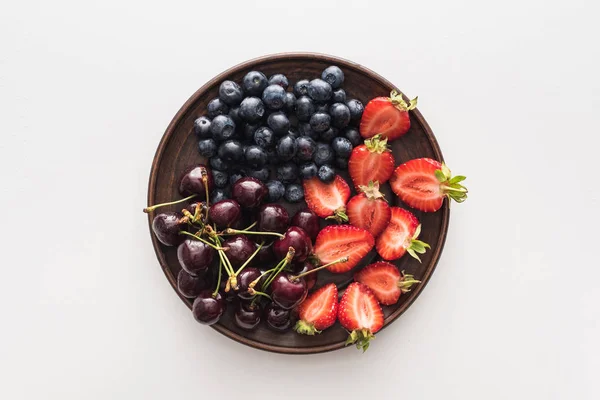 Vue de dessus des myrtilles douces, cerises entières et fraises coupées sur assiette — Photo de stock