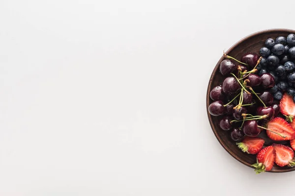 Vista superior de mirtilos doces, cerejas inteiras e morangos cortados no prato — Fotografia de Stock