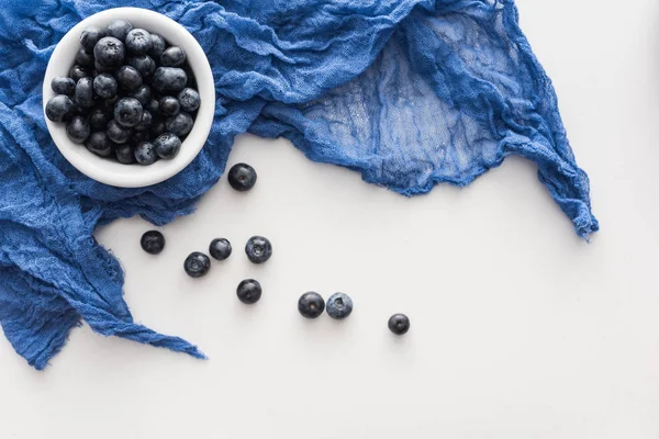 Süße Blaubeeren auf blauer Schale mit blauem Tuch — Stockfoto