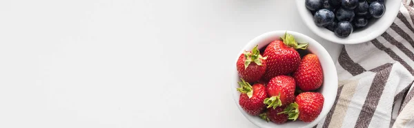 Panoramic shot of fresh and ripe strawberries and blueberries on bowls — Stock Photo