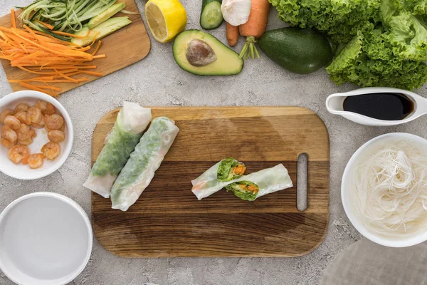 Vista dall'alto degli involtini primavera sul tagliere tra gli ingredienti — Foto stock