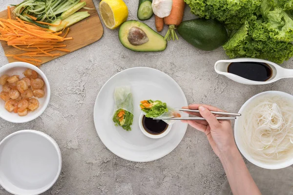 Top view of woman holding tasty spring roll with metal sticks — Stock Photo