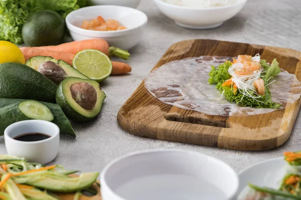 Cenoura, alface, macarrão, camarão e papel de arroz cortados sobre tábua de corte — Fotografia de Stock