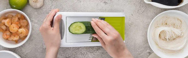 Panoramic shot of woman grating cucumber among ingredients — Stock Photo