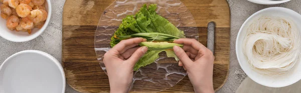 Panoramaaufnahme einer Frau, die geschnittene Avocado auf Salat, auf Schneidebrett legt — Stockfoto