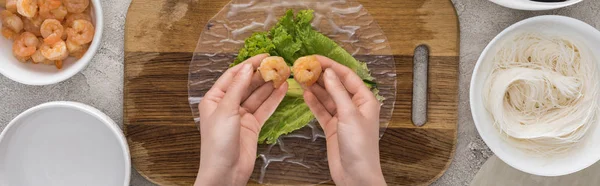 Panoramic shot of woman putting shrimps on lettuce, on cutting board — Stock Photo
