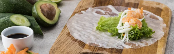 Plano panorámico de lechuga, fideos y camarones sobre papel de arroz, sobre tabla de cortar - foto de stock