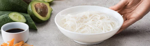 Plano panorámico de la mujer sosteniendo tazón blanco con fideos y agua - foto de stock