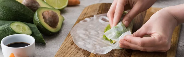 Panoramic shot of woman making spring roll on cutting board — Stock Photo