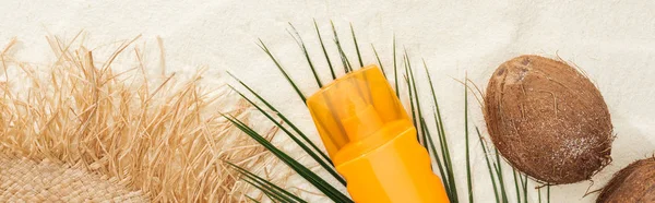 Vista superior de la hoja de palma, cocos y productos de protección solar con sombrero de paja en la arena, plano panorámico - foto de stock