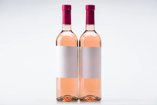 Dos botellas de vino rosa con etiquetas en blanco sobre fondo blanco - foto de stock