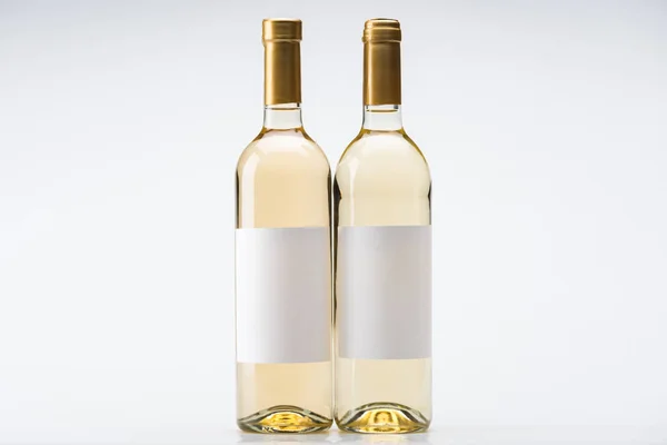 Пляшки білого вина з порожніми етикетками на білому тлі — стокове фото