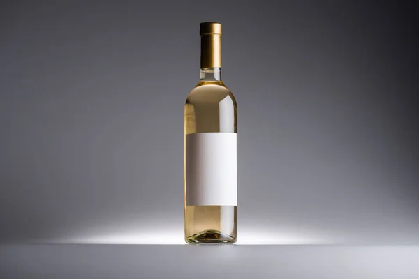 Flasche Weißwein und leeres Etikett auf dunklem Hintergrund mit Gegenlicht — Stockfoto