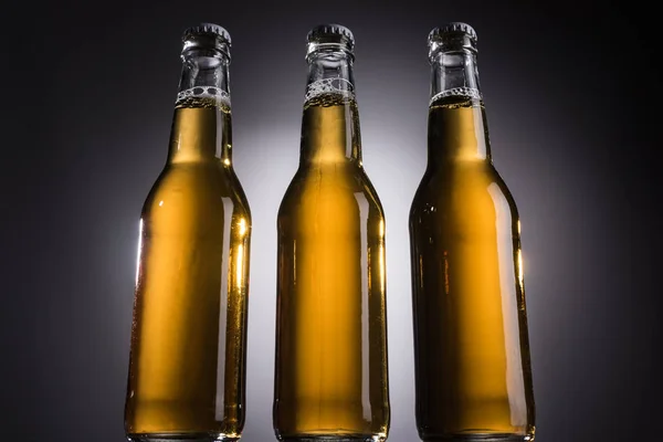 Niedrigwinkel-Ansicht von Glasflaschen mit Bier auf dunklem Hintergrund mit Gegenlicht — Stockfoto