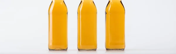 Three beer bottles in row isolated on grey, panoramic shot — Stock Photo