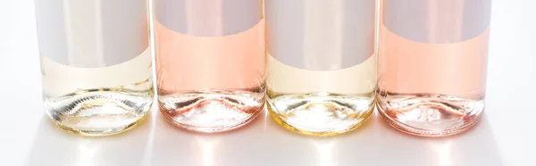 Close up view of bottles with rose and white wine, empty labels and back light, panoramic shot — Stock Photo