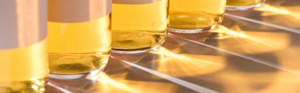 Vista de perto de garrafas de cerveja com luz e sombra, tiro panorâmico — Fotografia de Stock