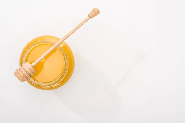 Top view of jar with honey and wooden honey dipper on white background with copy space — Stock Photo