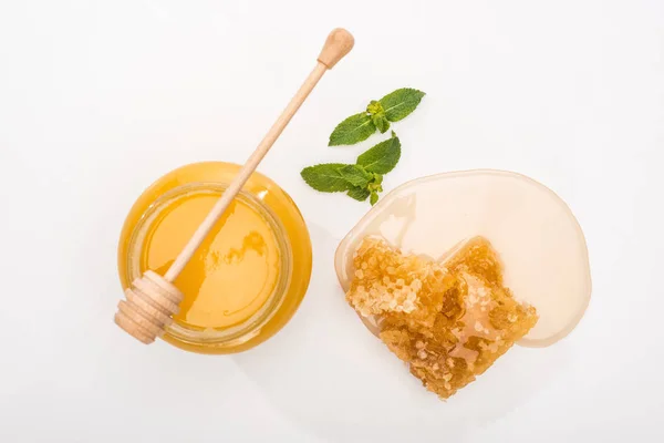 Vista superior do frasco com mel, hortelã, favo de mel e mel de madeira dipper no fundo branco — Fotografia de Stock