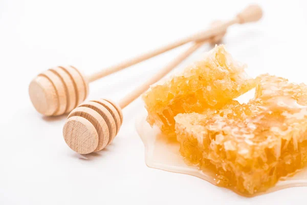 Favo de mel doce com mel perto de mergulhadores de mel de madeira no fundo branco — Fotografia de Stock