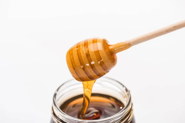Jarra com mel e mel de madeira dipper isolado em branco — Fotografia de Stock