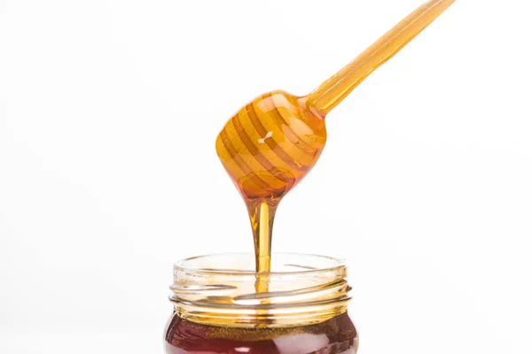 Wooden honey dipper with dripping delicious honey isolated on white — Stock Photo