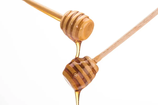 Деревянные медовые ковши с капельным сладким медом изолированы на белом — стоковое фото