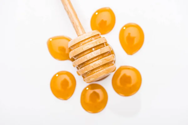 Top view of honey drops and wooden honey dipper isolated on white — Stock Photo