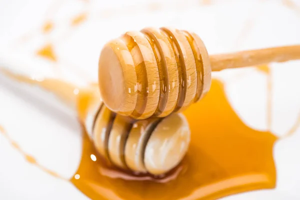 Close up view of honey puddle and wooden honey dippers isolated on white — Stock Photo