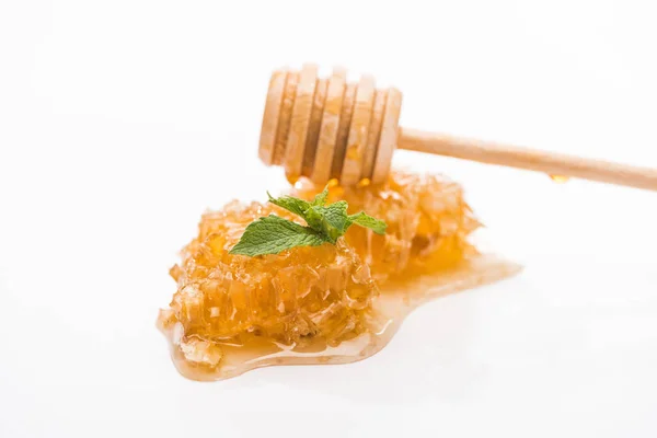 Вкусная сота с мёдом и зелеными листьями мяты возле деревянной ковши, изолированной на белом — стоковое фото