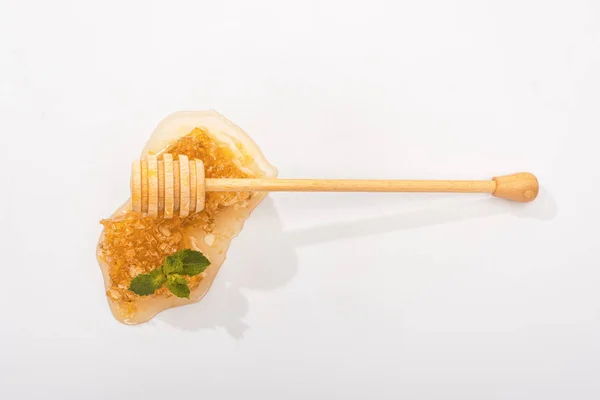 Top view of honeycomb with sweet honey, mint and wooden honey dipper on white — Stock Photo