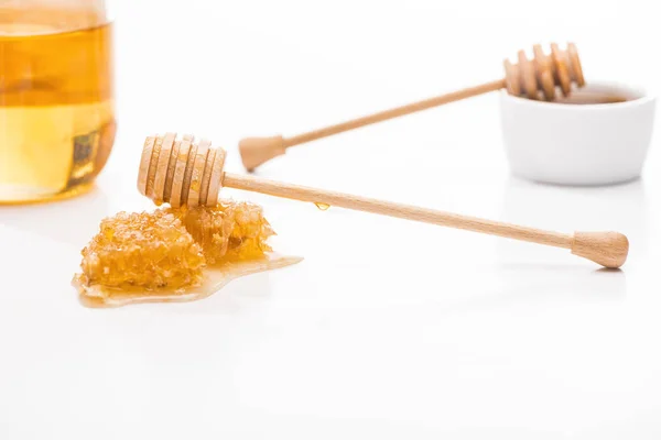 Selective focus of honeycomb with sweet honey and wooden honey dippers near jar isolated on white — Stock Photo