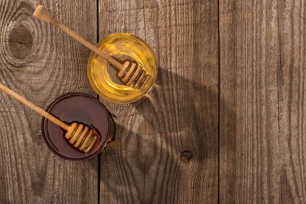 Top view of jars with honey and honey dippers on wooden table in sunlight — Stock Photo