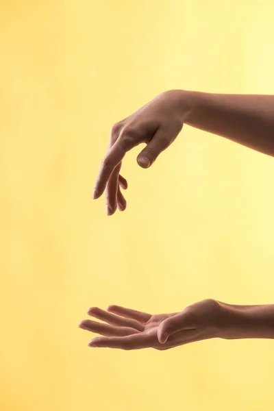 Vista recortada de la mujer con las manos gestuosas sobre fondo amarillo - foto de stock