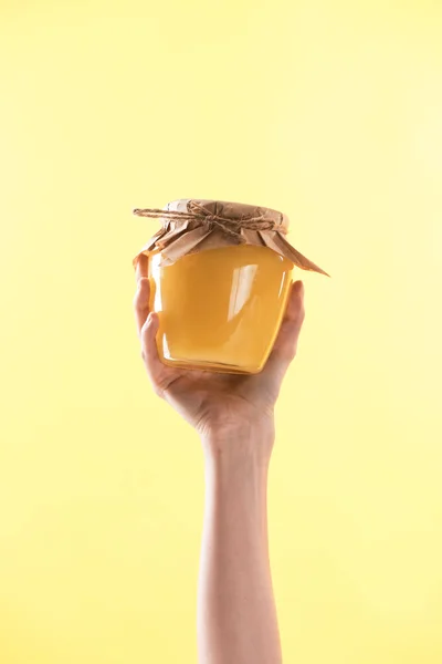 Cropped view of woman holding glass jar with delicious sweet honey in hand isolated on yellow — Stock Photo